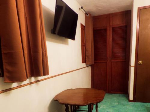 a room with a table and a television on a wall at Hotel Boutique Flores y Gemas in Mérida