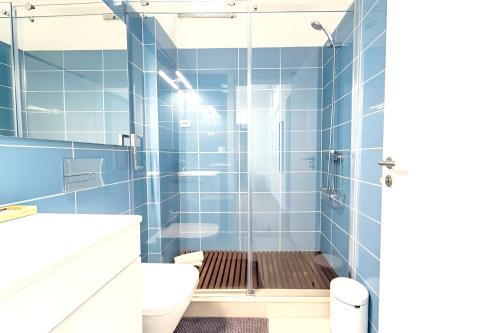 a blue tiled bathroom with a shower and a toilet at Biscainhos Flat By The Arch - Charming Apartments in the Historic Center in Braga