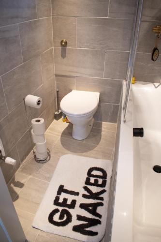 a bathroom with a toilet and a rug on the floor at Private room with own entrance and bathroom in London