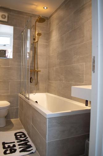 a bathroom with a tub and a toilet at Private room with own entrance and bathroom in London