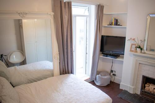 a bedroom with two beds and a television and a fireplace at Private room with own entrance and bathroom in London