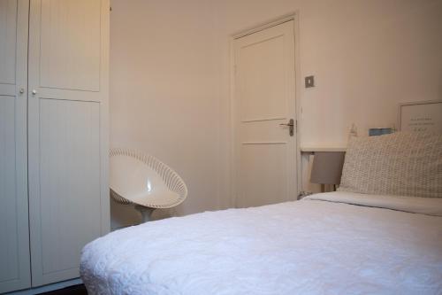 a white bedroom with a bed and a chair at Private room with own entrance and bathroom in London