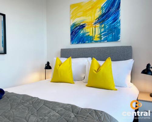 Un dormitorio con una cama con almohadas amarillas y una pintura en 1 Bedroom Apartment by Central Serviced Apartments - Walk Away From Main Attractions - Parking Available - Close to Bus and Train Station - Easy Access to City Centre - Wi-Fi - Fully Equipped - Monthly-Weekly Stay Offers, en Dundee