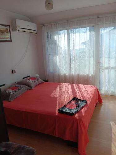 1 dormitorio con cama roja y ventana en Apartment Friends, en Sandanski
