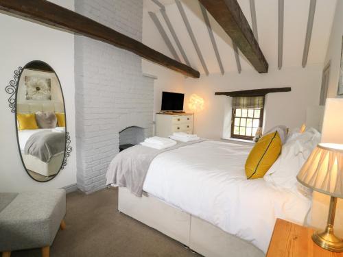 a bedroom with a large white bed and a mirror at Edmunds Cottage in Bedale