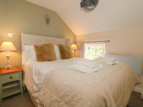 a bedroom with a bed with white sheets and a window at Loft Cottage in Bedale