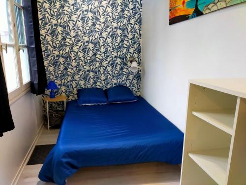 een klein blauw bed in een kamer met een muur bij T2 entre rivière et château centre Vitré in Vitré