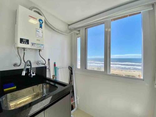 uma cozinha com vista para a praia a partir de uma janela em A melhor vista de Capão da Canoa em Capão da Canoa