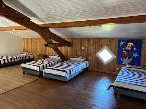 3 camas en una habitación con paredes de madera en Maison de rêve, en Boulogne-sur-Gesse