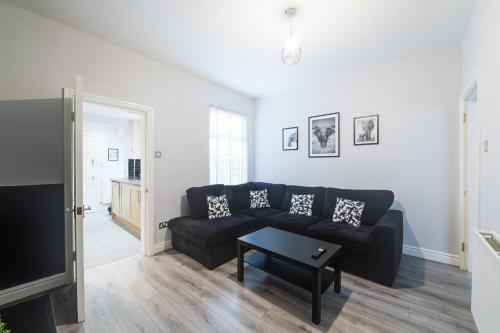 uma sala de estar com um sofá preto e uma televisão em Poppy's Project - July Road em Liverpool