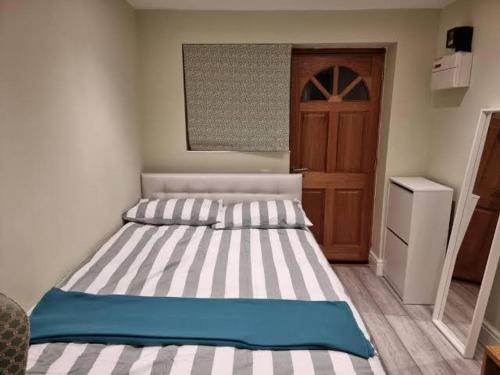 a bedroom with a bed with a striped mattress and a door at Apartemen/hotel in Jenggrik