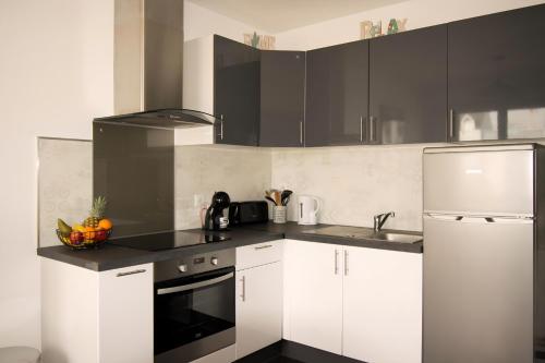 une cuisine avec des armoires blanches et un réfrigérateur blanc dans l'établissement Bel appart avec parking, proche centre et plages, à Lorient