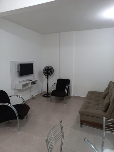 sala de estar con sofá, sillas y TV en Apartamento living, en São Vicente