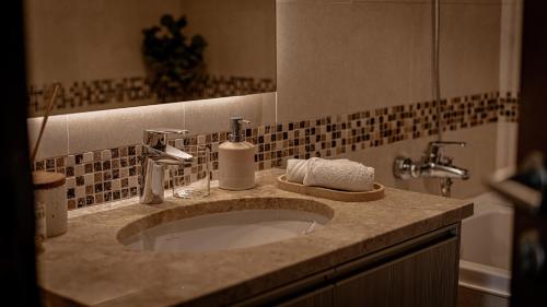een badkamerbar met een wastafel en een spiegel bij Voyage One Bedroom In Ansam in Abu Dhabi