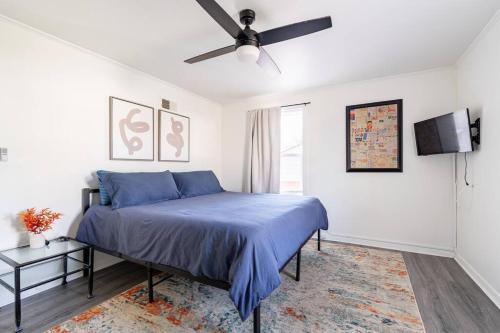 a bedroom with a blue bed and a ceiling fan at 4 Bedroom Bungalow - 5 min to Uptown Charlotte in Charlotte