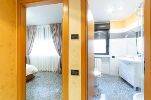 Un baño con lavabo, inodoro y ventana. en Melannie's Apartment, en Bérgamo