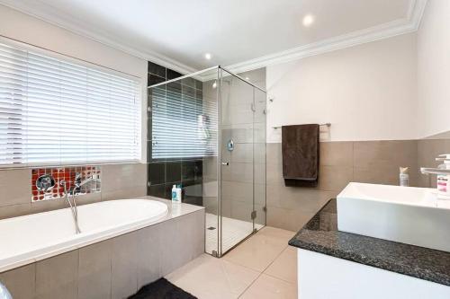 a bathroom with a tub and a sink and a shower at Luxurious, spacious & central in Sandton