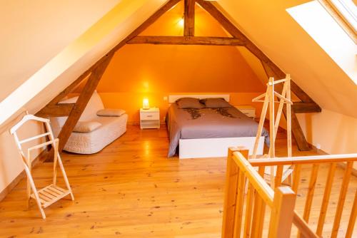 a attic bedroom with a bed and a ladder at Gîte normand authentique in Roiville
