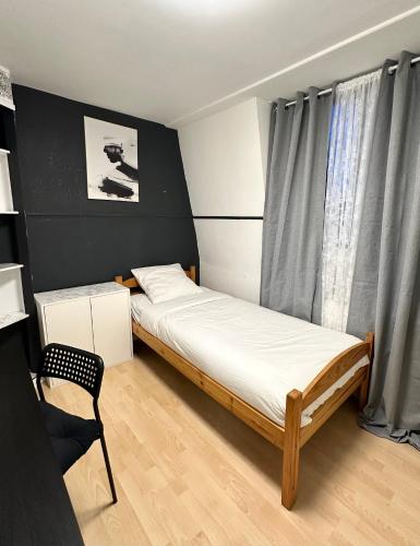 niewielka sypialnia z 2 łóżkami i krzesłem w obiekcie Une belle maison avec 2 chambre w mieście Croix