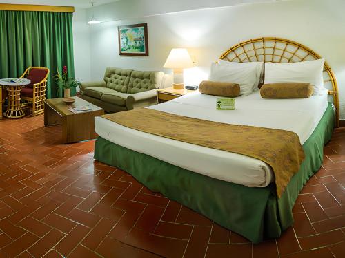 a bedroom with a large bed and a living room at Hotel Chicala in Neiva