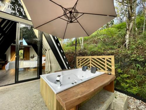 a bath tub with an umbrella on a patio at Ecoluxury Glamping in San Antonio de Pereira
