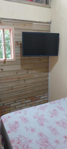 een slaapkamer met een flatscreen-tv aan de muur bij Morada Sol e Lua Container Guarda do Embaú com Ar condicionado in Guarda do Embaú
