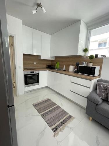 una cocina con armarios blancos y un sofá. en Двустаен апартамент за двама., en Burgas