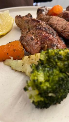 a plate of food with broccoli and meat and vegetables at Agora Farmhouse in Koman