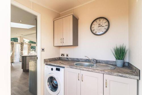 uma cozinha com um lavatório e um relógio na parede em Woodland Jewel Lodge with Hot Tub em York