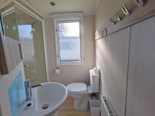 a bathroom with a sink and a toilet and a window at Golden sands beach activities sea holiday relax in Mablethorpe