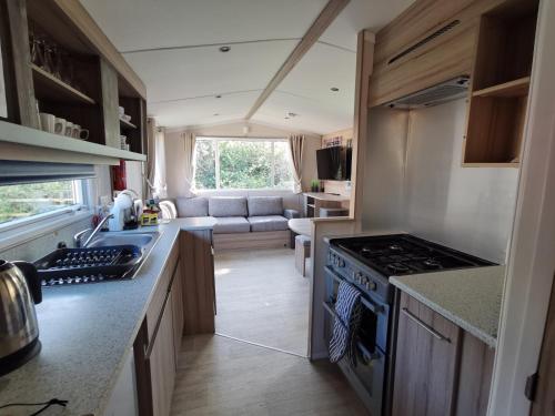 a kitchen with a stove top oven next to a living room at 8Berth- SmartTV- CloseToBeach- FamilyFriendly in Mablethorpe