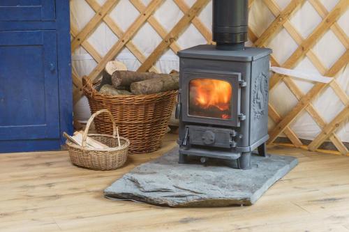 a wood stove in a room with two baskets at Wilding Yurt Stay in Broughton in Furness