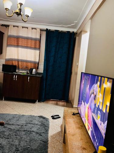 a living room with a flat screen tv and a table at Kampala Flat in Kampala