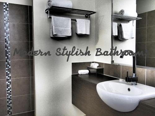La salle de bains est pourvue d'un lavabo blanc et d'un miroir. dans l'établissement Injune Motor Inn, à Injune
