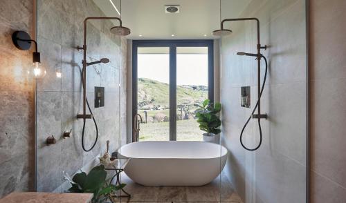 La salle de bains est pourvue d'une baignoire blanche et d'une fenêtre. dans l'établissement Ocean + Country - Wainui Beach, à Gisborne
