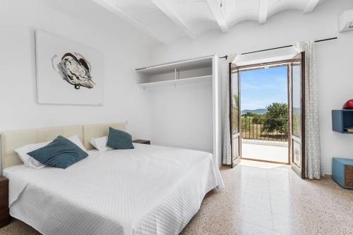 een witte slaapkamer met een bed en een glazen schuifdeur bij 8 Guests Large Villa near Bossa Beaches & Airport in San Jose de sa Talaia