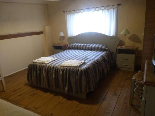 a bedroom with a bed with a striped bedspread and a window at La Catalina 2 in San Antonio de Areco
