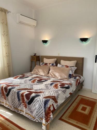 een slaapkamer met een bed met een dekbed en kussens bij Residence-Sassi in Nabeul