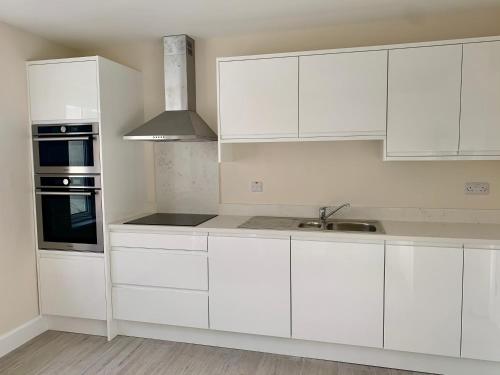 uma cozinha branca com armários brancos e um lavatório em Faul House em Clifden