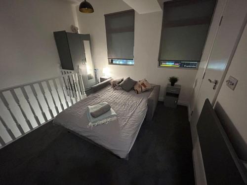 una piccola camera da letto con un letto con lenzuola e cuscini bianchi di City Studio Escape near Emirates a Londra