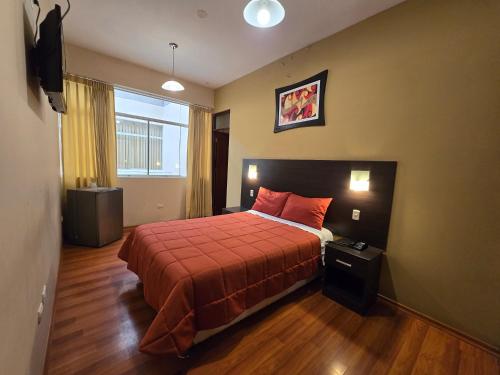 a bedroom with a bed with a red bedspread at Pacific Suites Hotel in Tacna