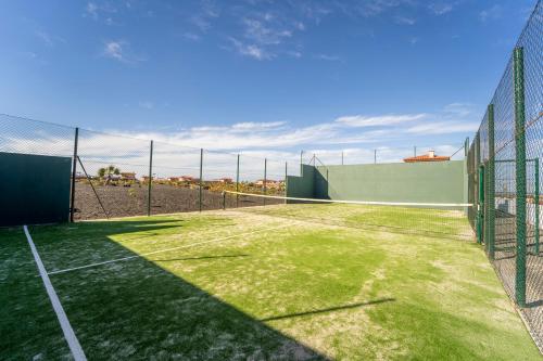 a tennis court with a net and grass at Villa Colibri Dorado in Lajares