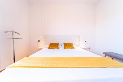 a white bed with two yellow pillows on it at Villa Colibri Dorado in Lajares