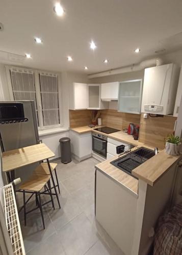 une cuisine avec des armoires blanches et une table et des chaises dans l'établissement Le Blue IVY Hyper centre 2 chambres Tout équipe, au Creusot