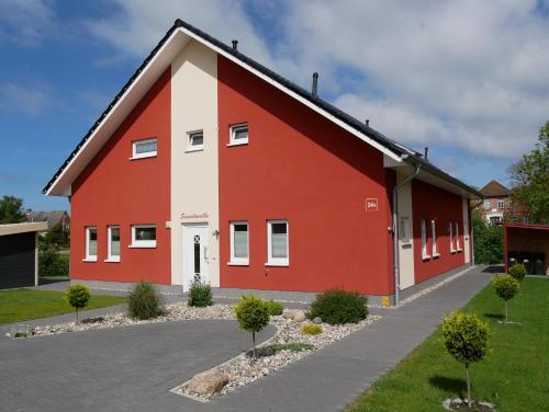 a red and white building with a driveway at Ferienhaus Lachmöwe in Fehmarn