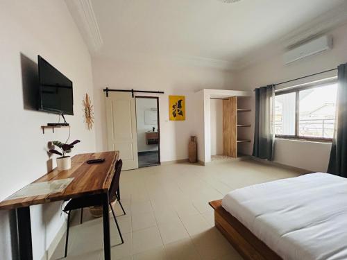 a bedroom with a bed and a desk and a television at Cocoon Guest House in Cotonou