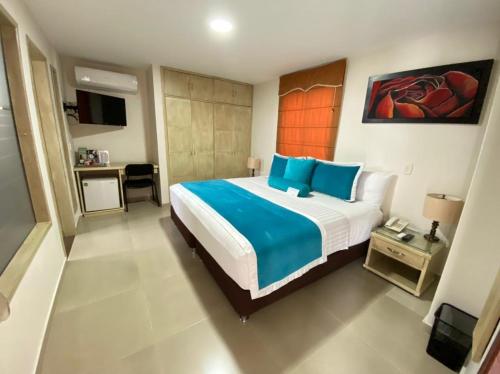 a bedroom with a large bed with blue pillows at Cabecera Country Hotel in Bucaramanga