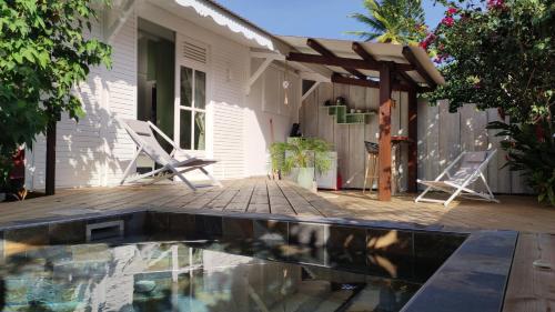 a patio with a pool and a house at Les Coulirooms - Suite avec jacuzzi et grande terrasse in Sainte-Anne