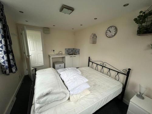 a bedroom with a bed with white sheets and a clock at Self Contained Annex in Potterspury