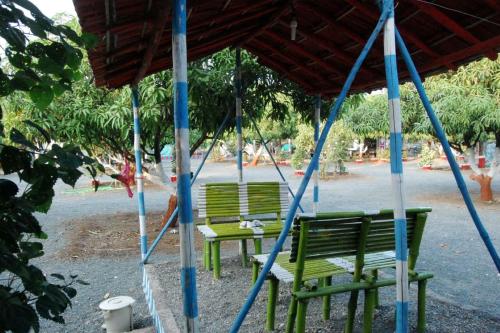 two green benches sitting under a canopy at a park at Gokul farm house in Sasan Gir